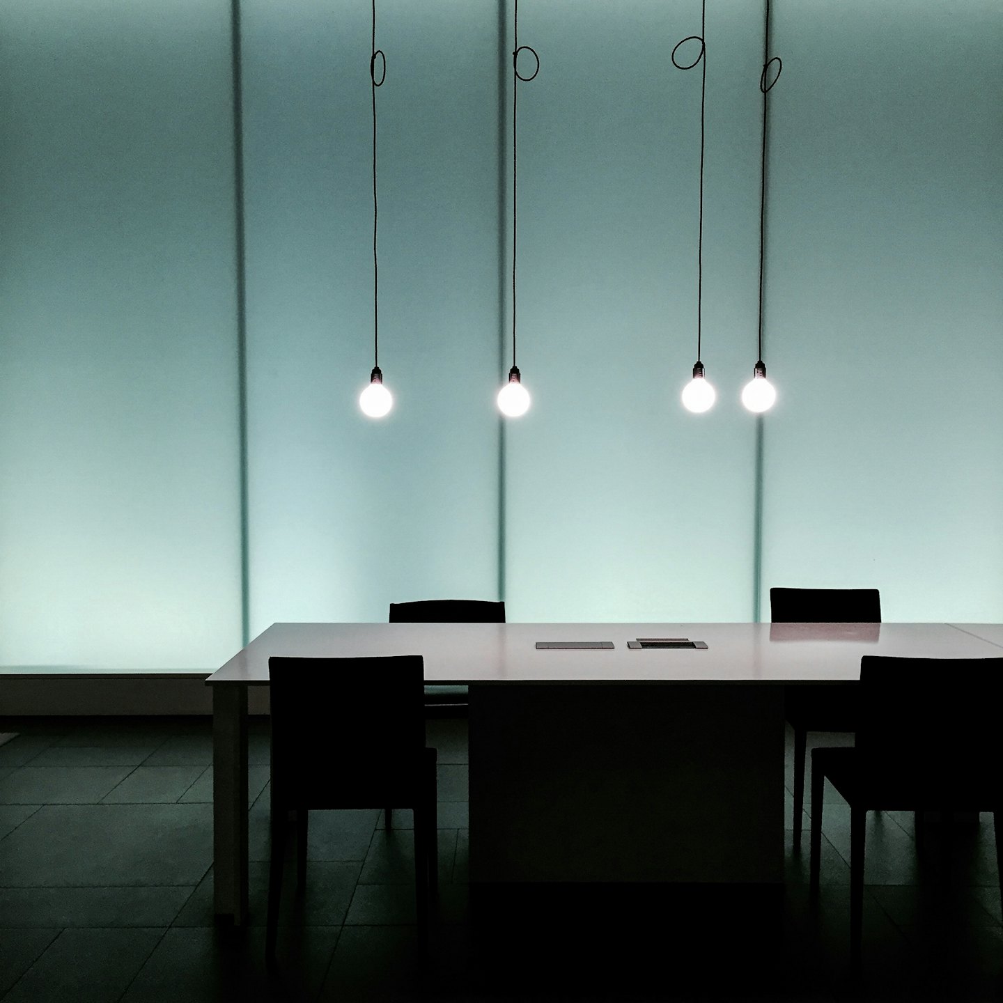 Modern conference room with a long table and hanging lights.