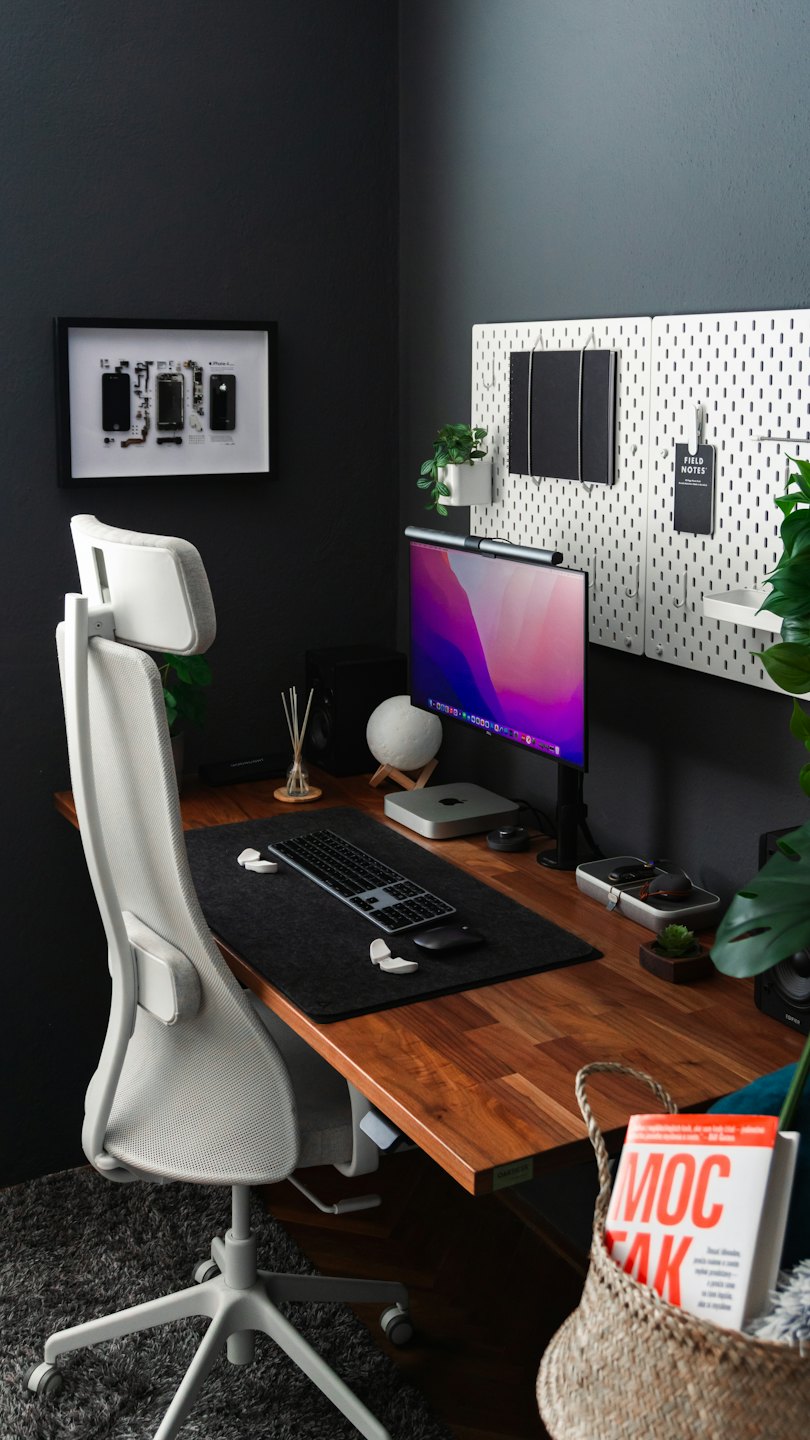 A modern desk with computer equipment and plants.