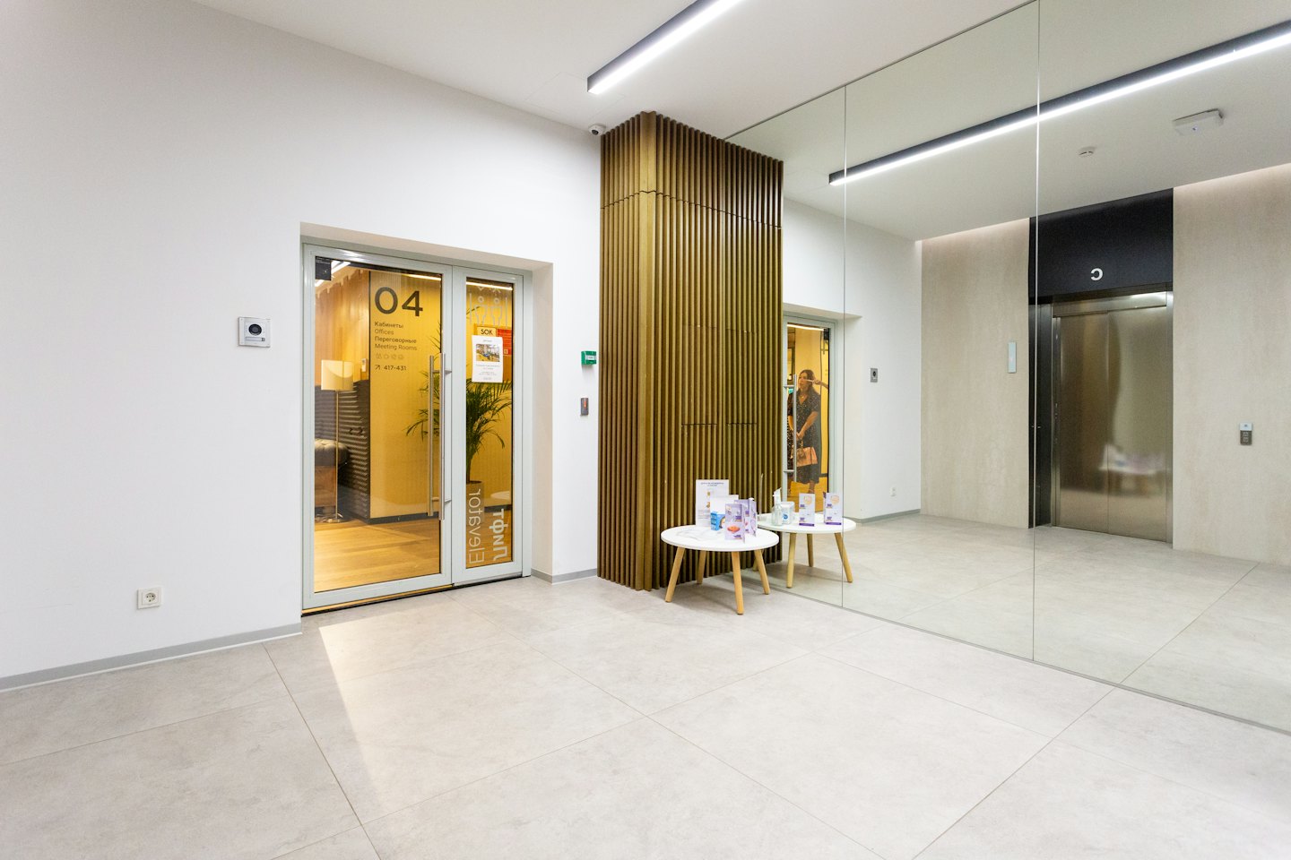 Modern office hallway with glass doors and slatted wood partitions.