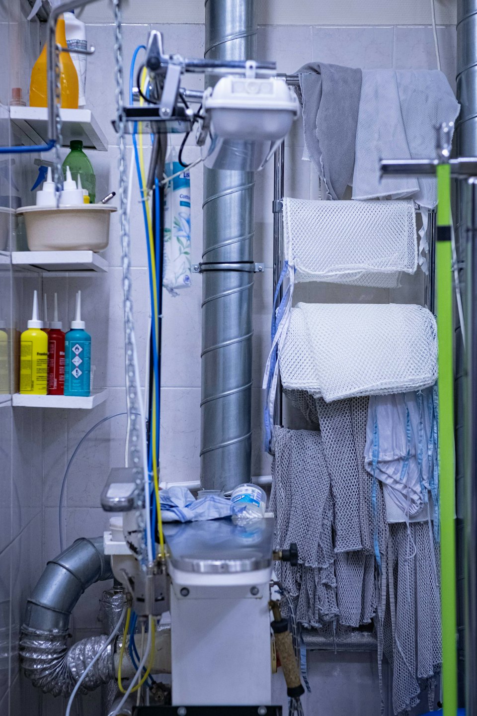 Industrial laundry area with ventilation pipes and cleaning supplies.
